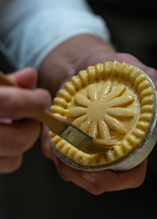 A pie being decorated by hand before baking